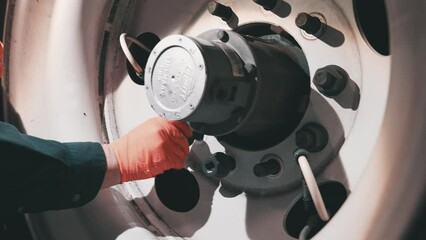 handheld close up mechanic with orange gloves ties lug nuts bolts on a trailer. head lamp turned on in dark environement