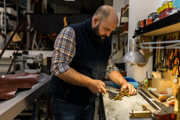 Focused craftsman working in leather workshop