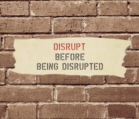 Naklejka premium Old time brick wall background with text inscription DISRUPT BEFORE BEING DISRUPTED, means business must start to transform strategically to advance technology and digital capability to deal with it