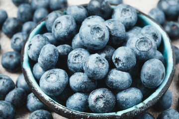Blueberries with water drops in a ceramic bowl and scattered around.