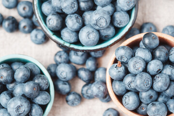 Three ceramic bowls with blueberries and berries scattered around. Top view.
