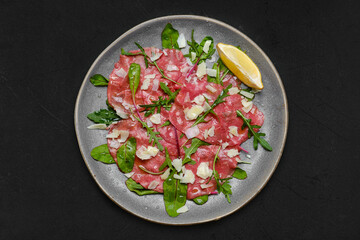 Top view of marbled beef carpaccio on black background