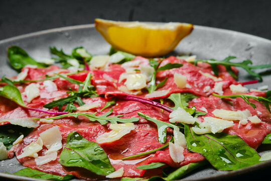 Marbled beef carpaccio on black background, closeup