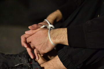 A young man with his hands tied.