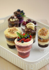 Homemade desserts in glass jars. Traditional unbaked Italian dessert on a white background. Cake with coffee, berries, fruits and mascarpone cream.