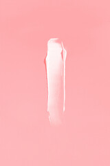 White cream smear on a pink background. Vertical photography.