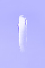 White cream smear on a purple background. Vertical photography.