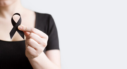 The woman 's hand holds black Ribbon for symbol Melanoma and skin cancer. Narcolepsy, Primary Biliary Cirrhosis, Sleep Apnea Disorders