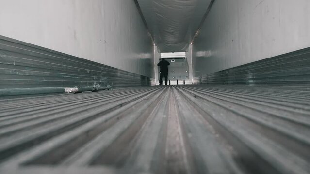 truck driver doing an inspection inside of a emty reefer trailer. Low angle