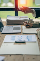 Group of business people writing with ballpoint pen on document with graph close up Businessman working and pointing at financial diagram and analyzing documents on office table vertical image