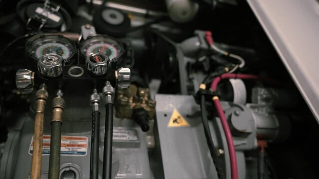 close up of a working engine inside a reefer trailer. Belts rotating and gauges.