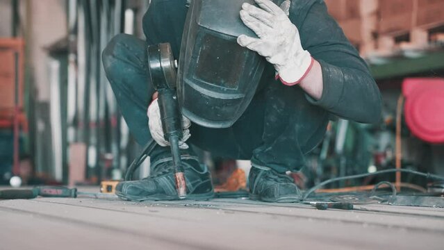welder mechanic worker working and keeps welding protective helmet on his head