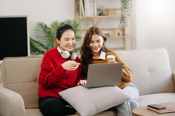 Two asian students learning together online with a laptop, tablet and tutor together in liveing room