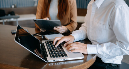 Fototapeta premium Team business meeting presentation. Hand businessman working project in modern office.Laptop computer and tablet and smart phone on white desk in morning light