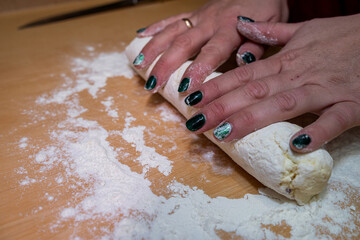 close-up of female hands rolling out sweet dough for baking