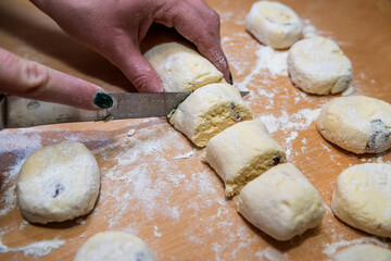 professional baker with knife cuts the raw sausage dough into even small pieces
