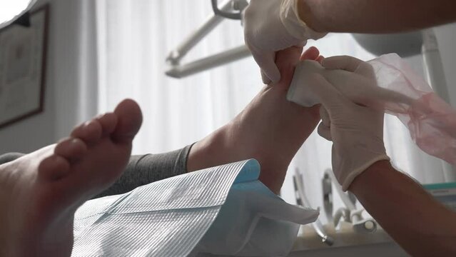 Professional orthopedist in disposable gloves using laser equipment to scan patient's feet conditions and establish diagnosis, podiatrist examining barefoot patient, consulting and doing prescription