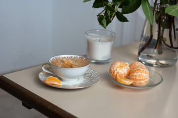 home decor. tea cup and vanila candle with piled mandarins