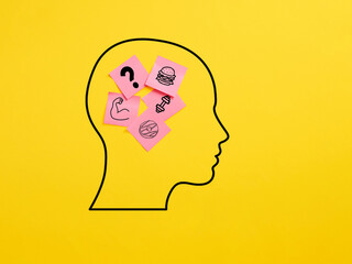 The dilemma between exercising and fitness or eating fast food. Sticky note papers in a human head symbol with food and health icons.