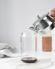 Mocha latte being poured into a can shaped glass, iced mocha and chocolate syrup