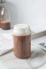 Mocha latte with whipped cream in a can shaped glass, iced mocha with foam and chocolate syrup