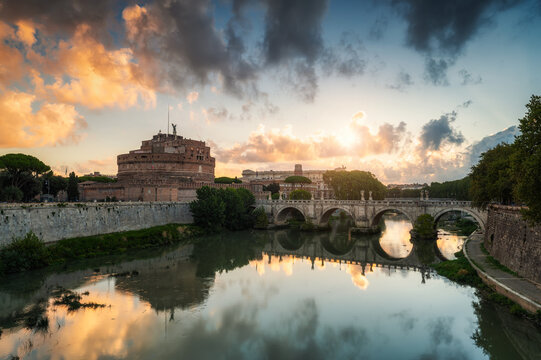 Fiery clouds at sunrise above medieval St. Angelo castle and the bridge over Tiber river in Rome, Italy.