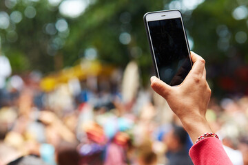 Close-up of a hand from the crowd filming the event on a cell phone