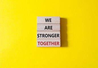 We are stronger together symbol. Wooden blocks with words We are stronger together. Beautiful yellow background. We are stronger together concept. Copy space.