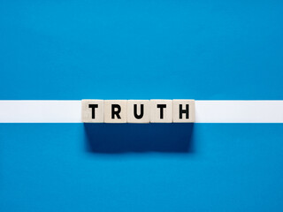 The word truth on wooden cubes on blue white background. Discovering the truth concept.