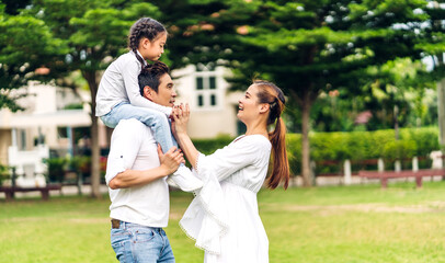 Fototapeta premium Portrait of enjoy happy love asian family father and mother holding hug cute little asian girl child smiling play and having fun moments good time in summer park at home.