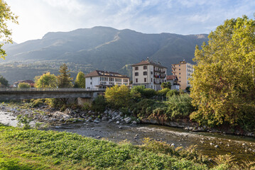 Fototapeta na wymiar City of Gravellona Toce with the Strona stream and the bridge in Corso Milano (street Milano) which leads to the city centre, Italy. Province of Verbano Cusio Ossola in Piedmont region