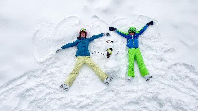 Ski vacation concept: woman and young boy in snow top view