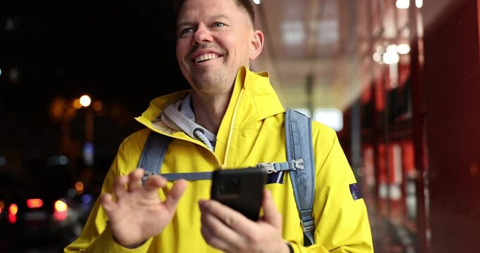 Male courier looking at mobile phone and waving to customer for food delivery 4k movie slow motion