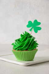 St. Patrick's Day tasty cupcake with green whipped cream decorated clover on white background....