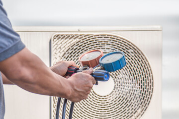 A technician checks the operation of the air conditioner,checks the pressure, adds refrigerant.