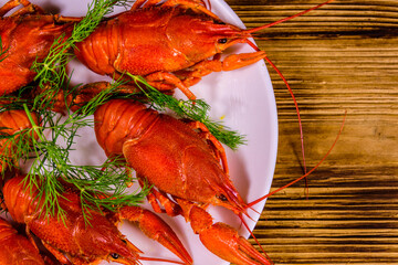 Plate with boiled crayfishes on wooden table. Top view