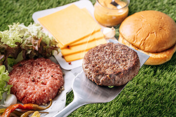 barbecue burger cutlet. barbeque concept in nature. barbecue spatula with a burger patty on it