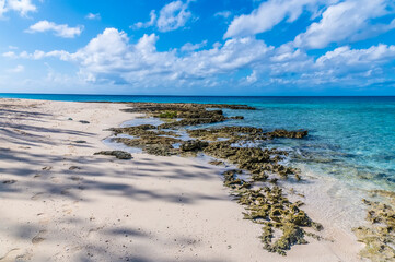 A view out to sea from the rocky shoreline in a deserted bay on the island of Eleuthera, Bahamas on a bright sunny day