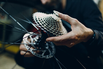 Mechanic repairman assembling gear sprocket transmission custom bicycle in workshop - obrazy, fototapety, plakaty