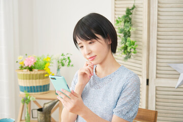 家でスマホを使う女性