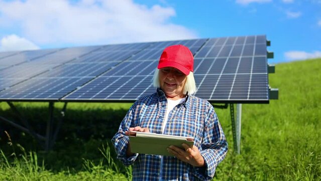 An female engineer is checking with tablet an operation of sun and cleanliness on field of photovoltaic solar panels on a sunset. Technology, electricity, service, green, future 