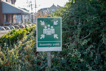 Green information sign locating a fire assembly point in a park 