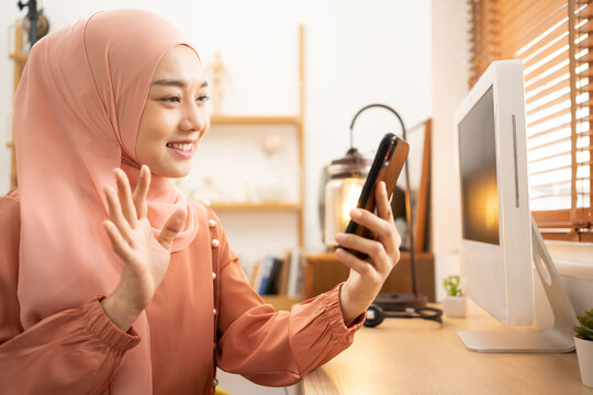 Asian woman Muslim Student wearing Hihab using mobile phone for VDO Call. Happy using internet for modern life.