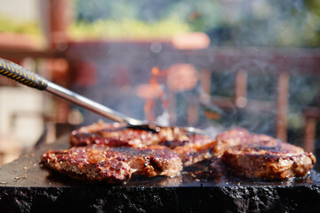Barbecue beef burger steak. Cutlet meat placed on grill stone with fire.