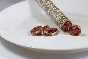 Slicing sausage with mold on a white plate on a white background.