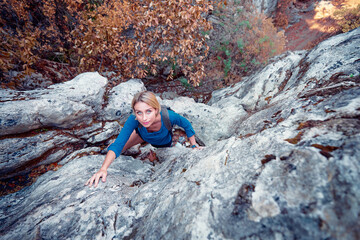 Obraz premium Young woman hiker climbing rock on mountain cliff.