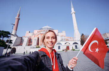 Enjoying vacation in Istanbul. Young traveling woman with national turkish flag taking selfie on...
