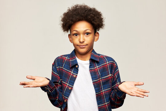 I Have No Idea. Portrait Of Confused African American Boy Kid Posing In Front Of Camera With Puzzled Facial Expression, Shrugging With Astonished Face After Mom Asking Him About School Things