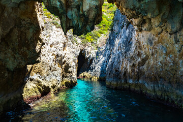 View of a grotto with crystal clear blue and turquoise waters and a rugged, overgrown coastline that gives a wonderful play of colors, Zakynthos, Greece
