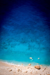 Fototapeta premium Beautiful crystal clear blue and turquoise waters next to a sandy beach with large stones in Myzithres, Zakynthos, Greece